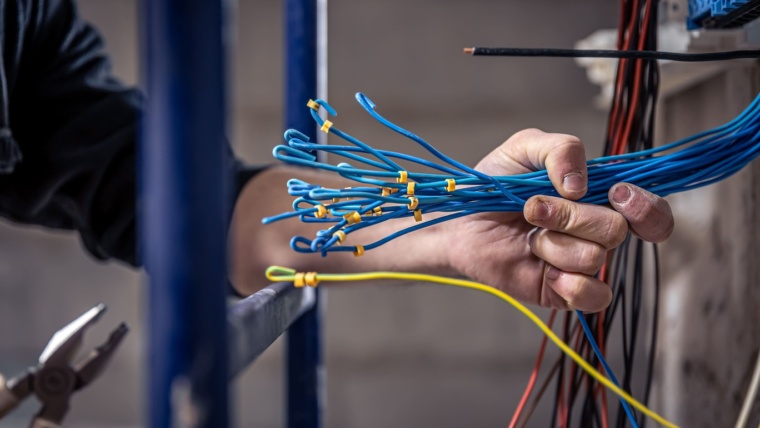 male electrician works switchboard with electrical connecting cable 1