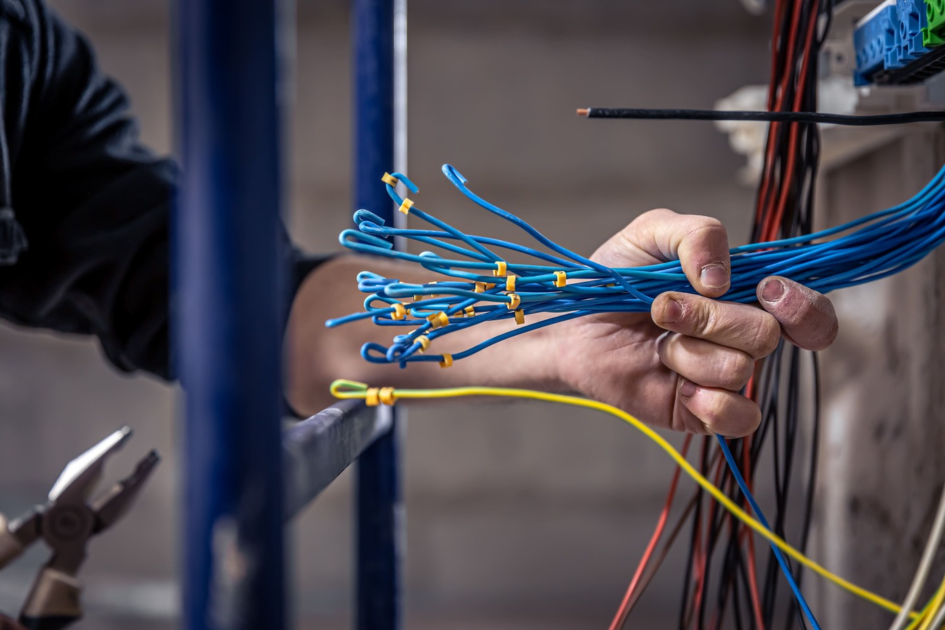 male electrician works switchboard with electrical connecting cable 1